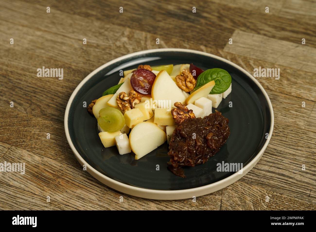 Différents types de fromage sur une assiette avec des raisins et des noix Banque D'Images