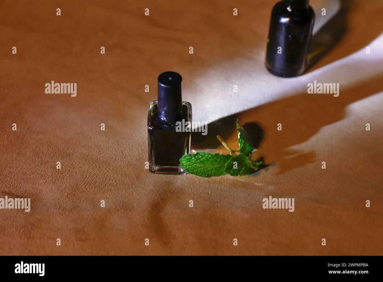 Vue de dessus de bouteille avec huile essentielle de menthe ou eau tonique sur fond brun avec la lumière du soleil Banque D'Images