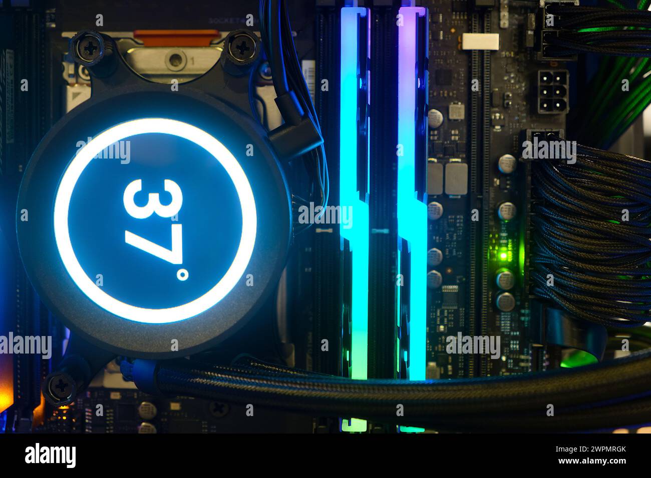 Gros plan pompe de refroidissement sur le support CPU de la carte mère avec affichage de la température numérique et voyant RGB multicolore indiquant l'état de fonctionnement Banque D'Images