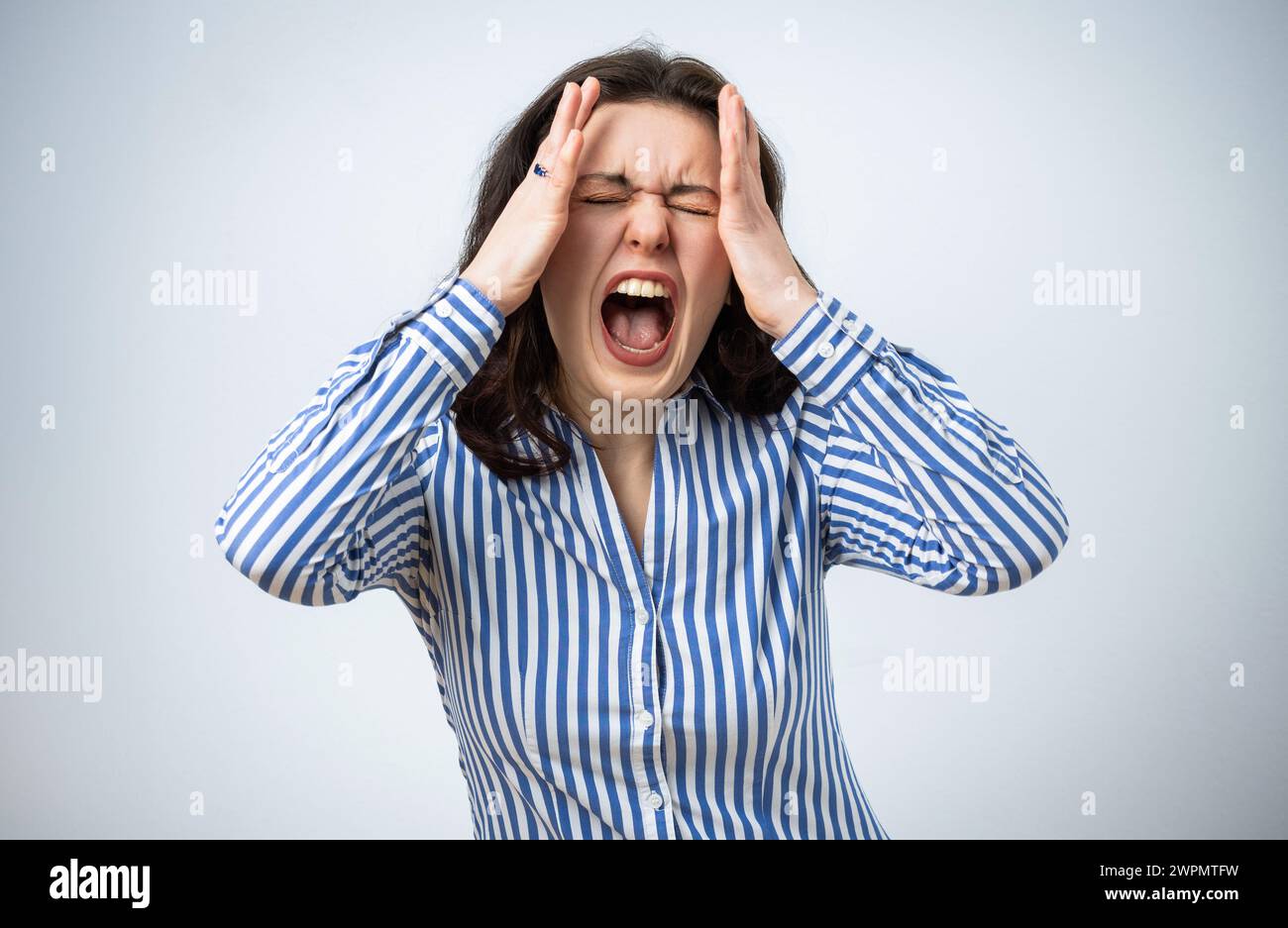 Femme frustrée en colère criant et tenant sa tête, isolée sur fond gris Banque D'Images