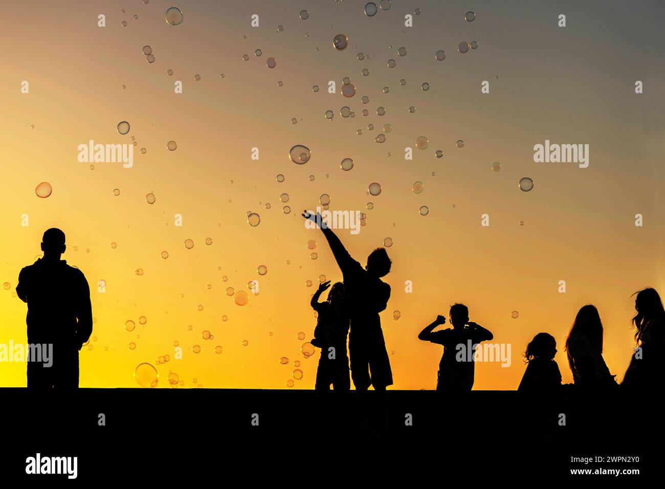 Enfants jouant avec de grandes bulles sur la promenade au coucher du soleil, Meloneras, Gran Canaria, Espagne, Europe Banque D'Images