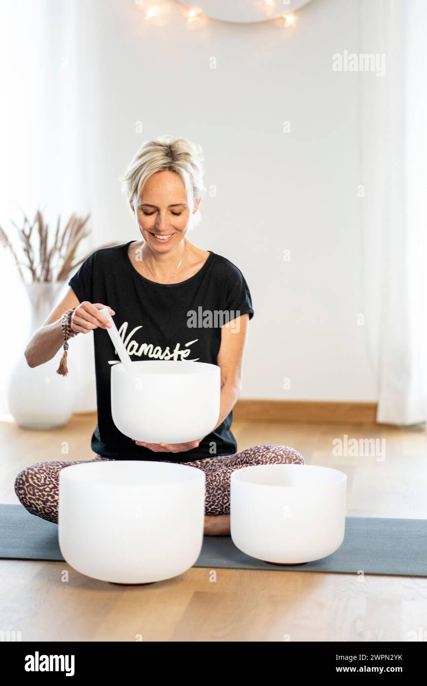 Femme jouant assise avec des bols chantants en cristal, exercices de méditation, Hambourg, Allemagne Banque D'Images