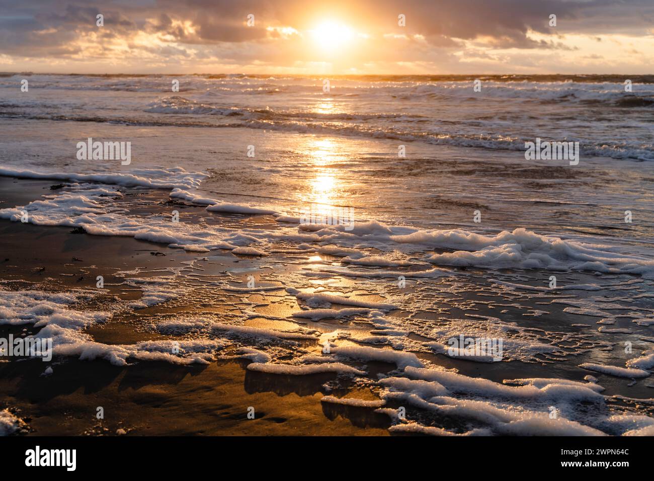 Coucher de soleil sur la plage ouest sur Norderney, le soleil se reflète dans l'eau peu profonde, les couleurs chaudes, l'atmosphère du soir Banque D'Images