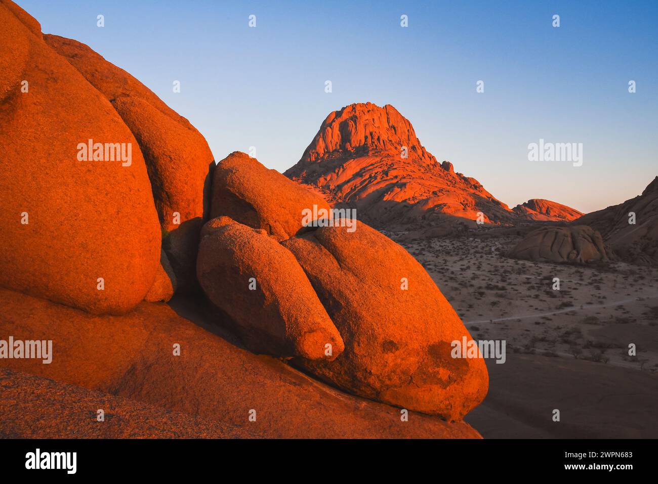 Spitzkoppe dans la lumière chaude du lever du soleil avec des formations rocheuses au premier plan en Namibie, Afrique Banque D'Images