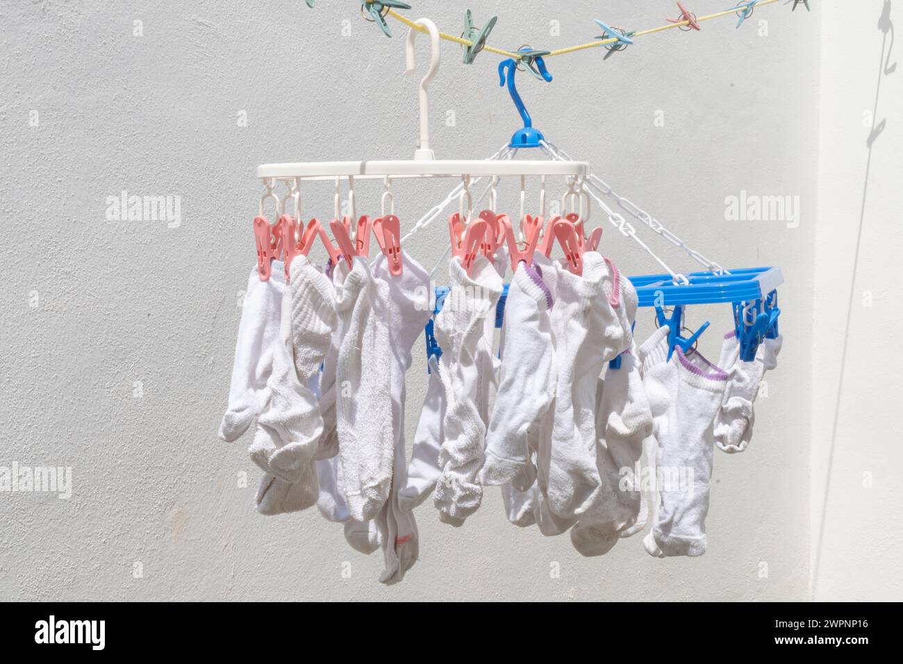 Chaussettes blanches suspendues à l'extérieur sur la corde à linge pour sécher à la lumière du soleil Banque D'Images