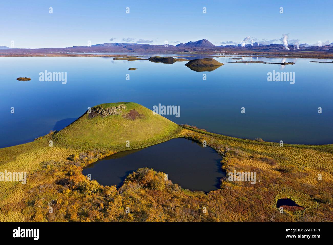 Pseudocratère à Myvatn près de Skrutustadir. Vue sur Hlidarfjall et les colonnes de vapeur des centrales géothermiques du volcan Krafla et Namaskard. Banque D'Images