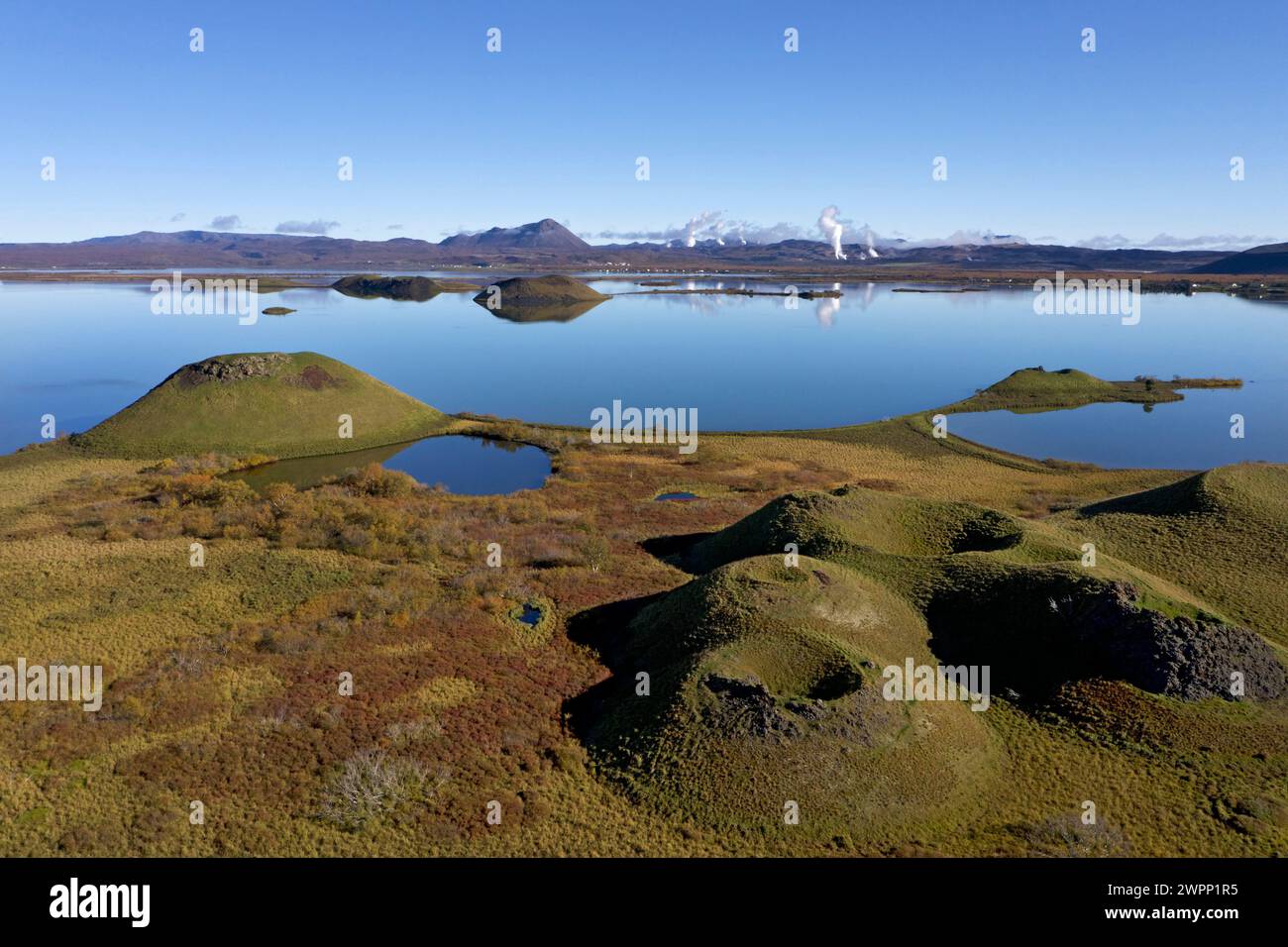 Pseudocratère à Myvatn près de Skrutustadir. Vue sur Hlidarfjall et les colonnes de vapeur des centrales géothermiques du volcan Krafla et Namaskard. Banque D'Images