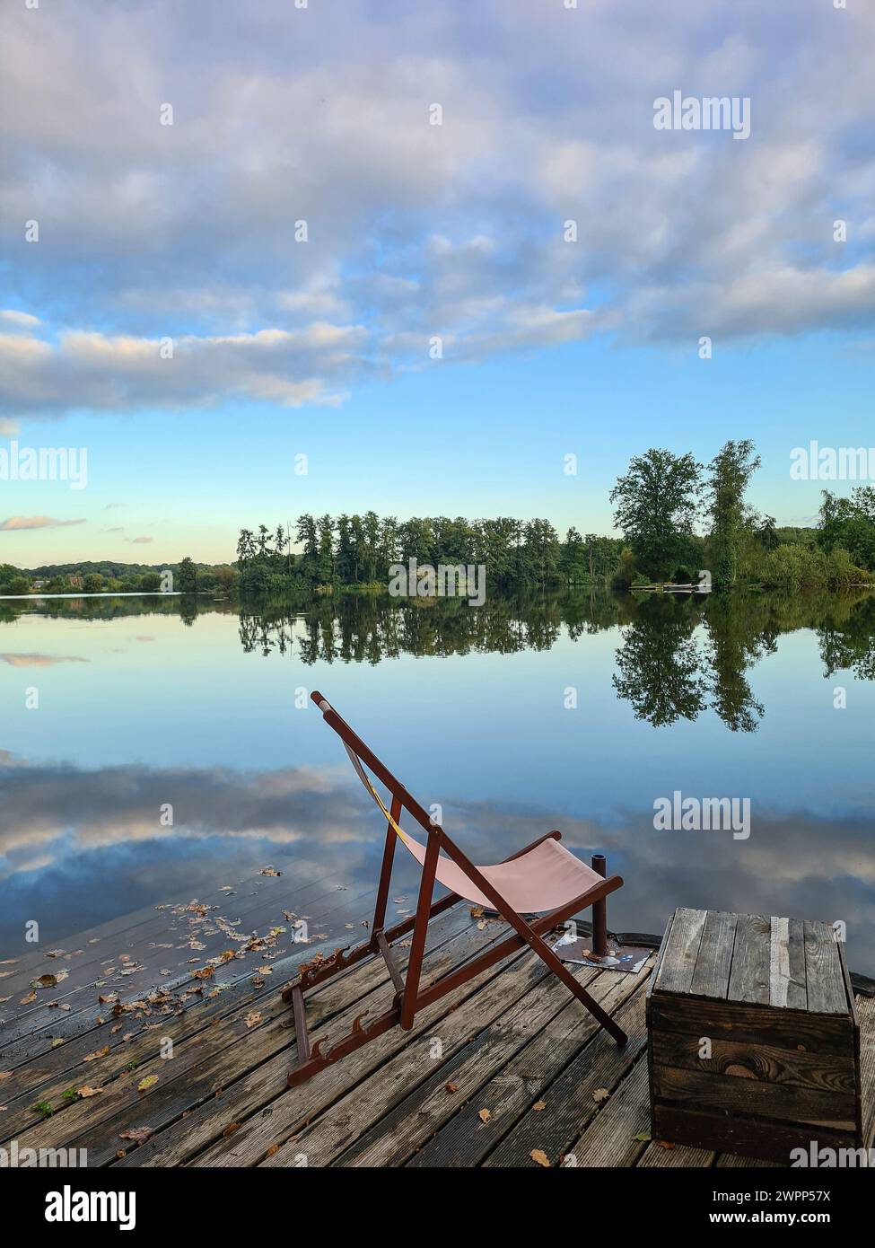 Une chaise longue se tient sur une plate-forme en bois sur le bord du lac, vue sur l'eau et le ciel avec des nuages, Wannsee, Berlin, Allemagne Banque D'Images