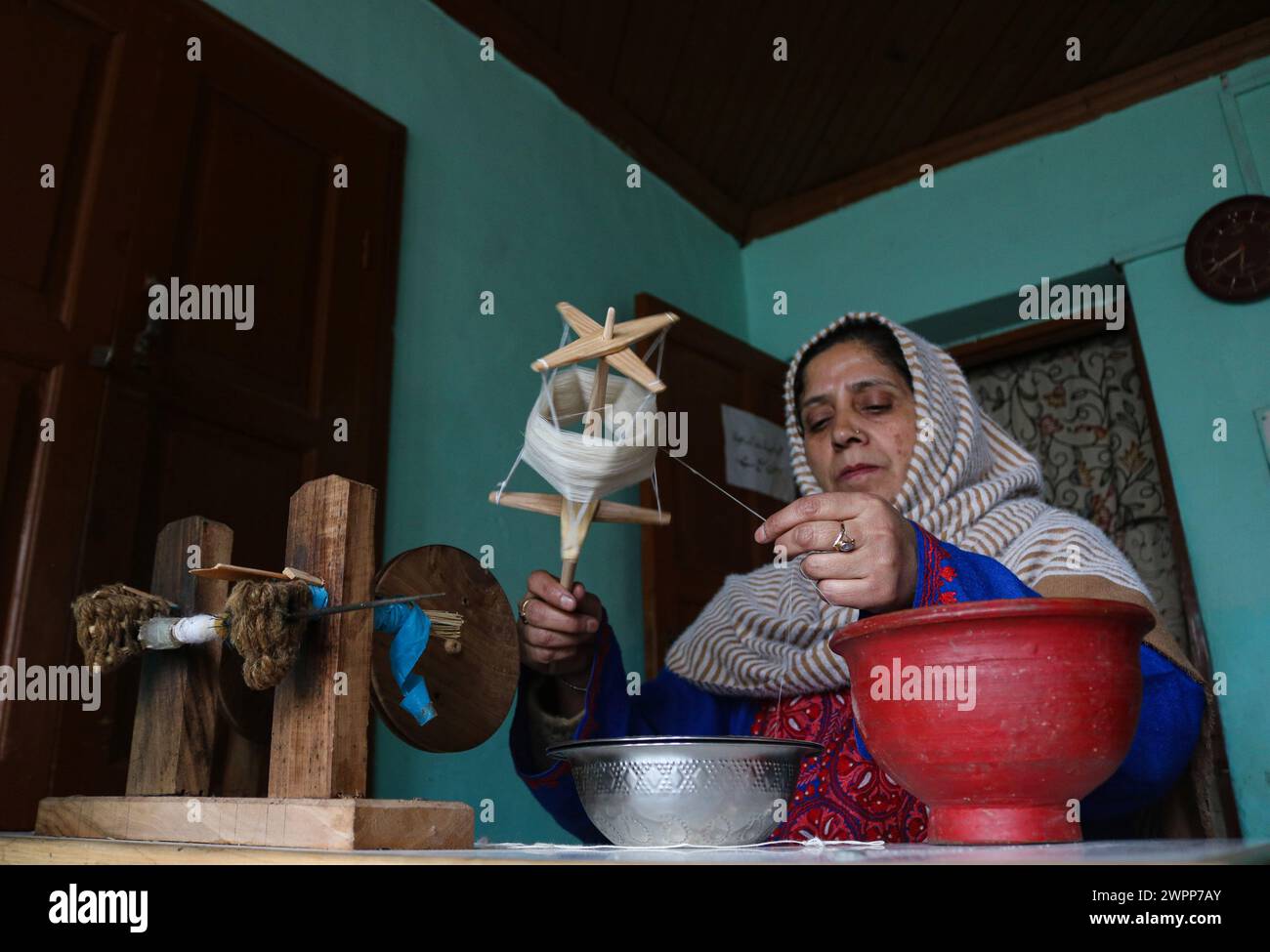 Non exclusif : 08 mars 2024, Srinagar, Inde : une femme file un fil pashmina avec une roue traditionnelle connue sous le nom de 'Yendir' dans un atelier sur In Banque D'Images