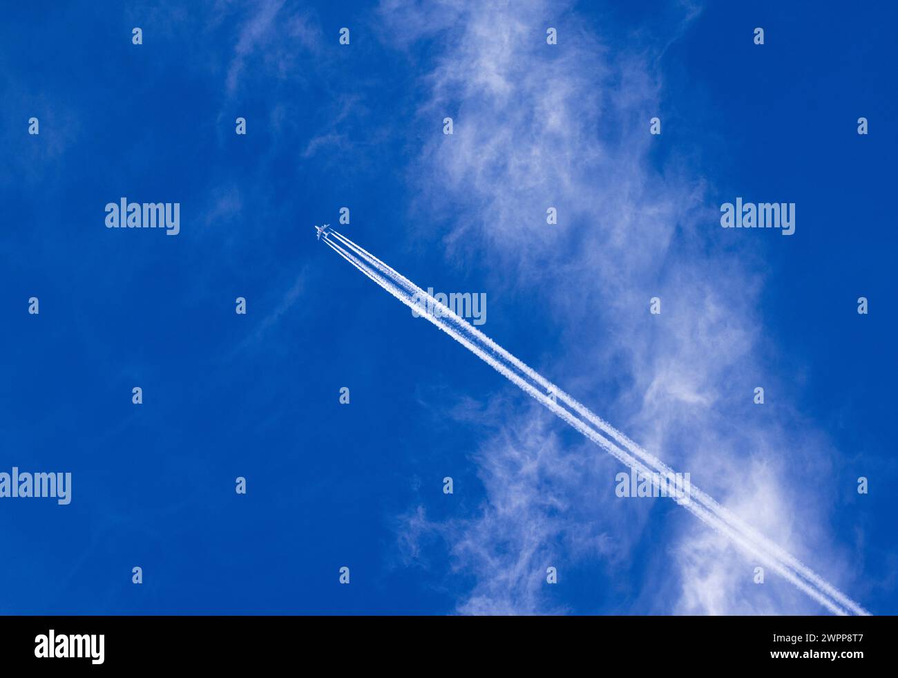 Nuages de cirrus volés par le vent sur un fond de ciel bleu, traînées d'avions qui passent Banque D'Images