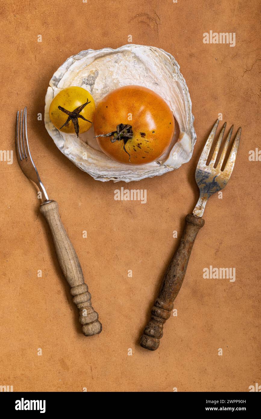 Nature morte avec tomate, gros plan, coquille comme bol, fourchettes Banque D'Images
