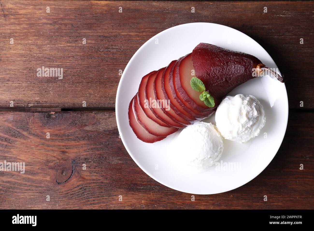 Savoureux vin rouge poché poire et crème glacée sur table en bois, vue de dessus. Espace pour le texte Banque D'Images