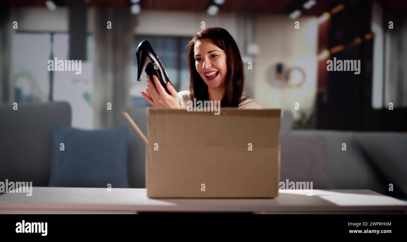 Smiling Young Woman Sitting on Sofa Déballage colis reçu Banque D'Images Smiling Young Woman Sitting on Sofa Déballage colis reçu Banque D'Images