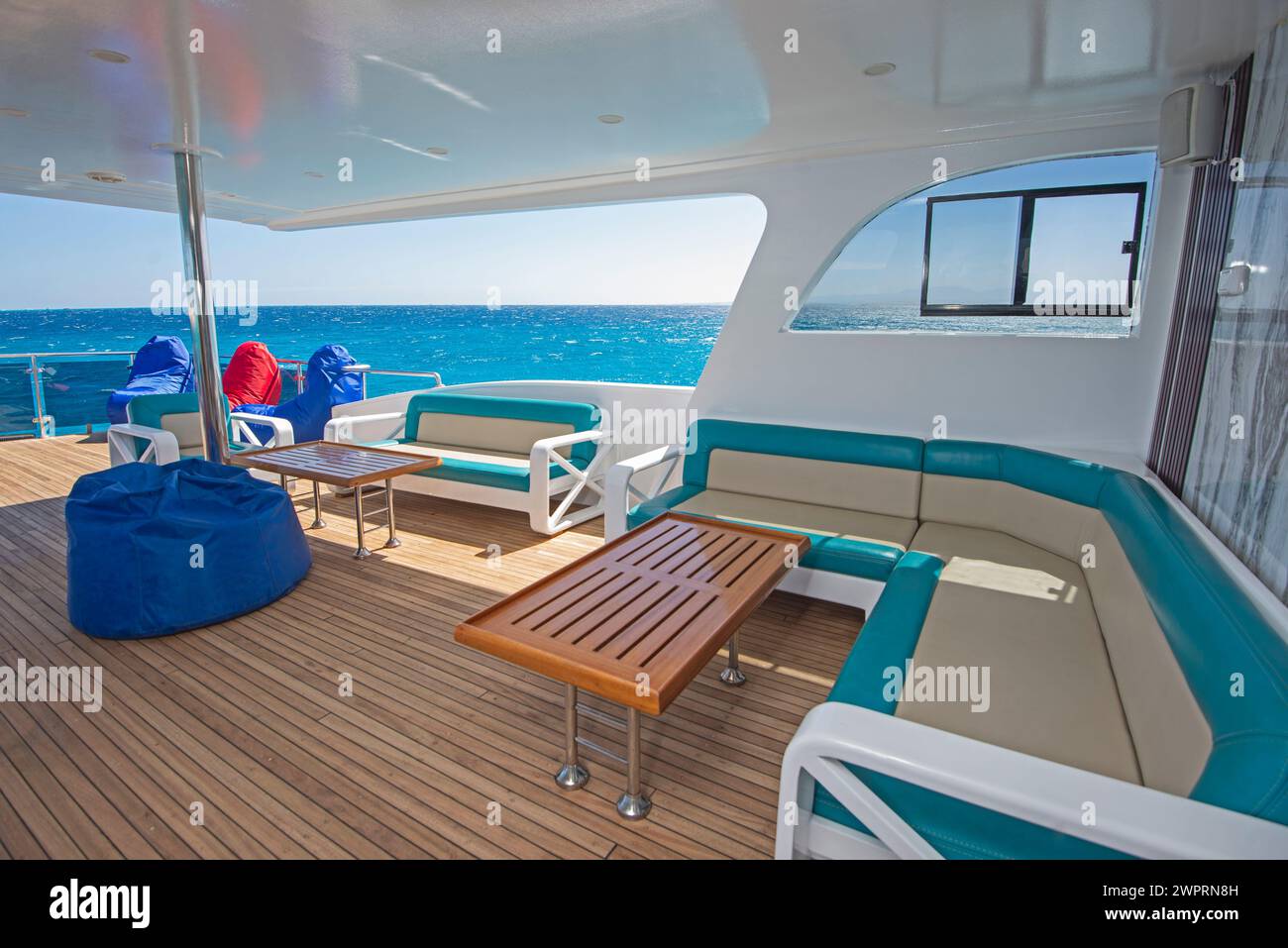 Terrasse en bois de poupe en teck d'un grand yacht à moteur de luxe avec chaises table de canapé et vue sur la mer tropicale arrière-plan Banque D'Images