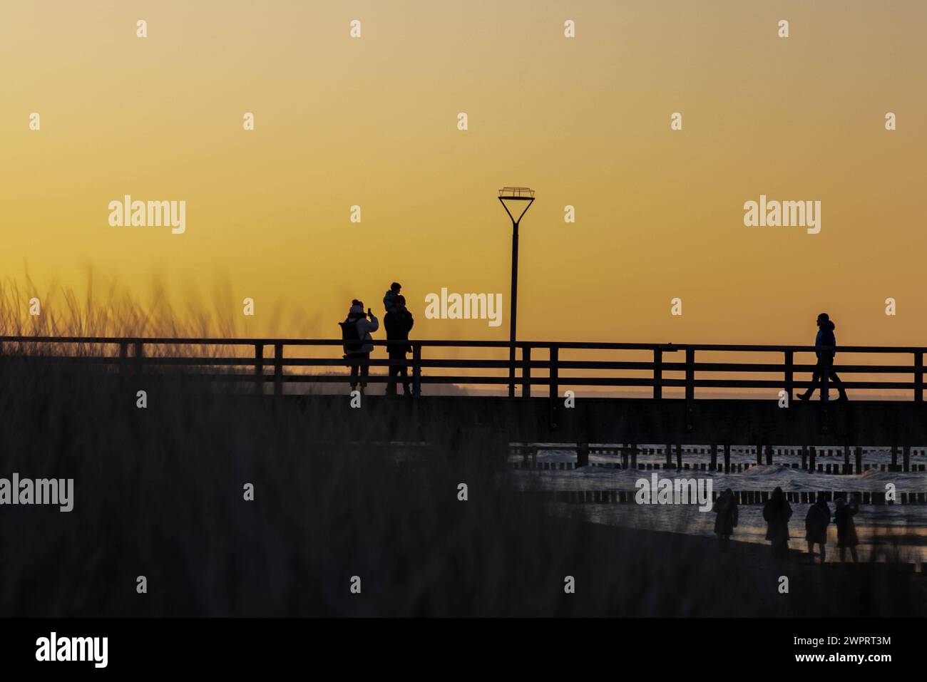 Seebrücke Zingst an der Ostsee Zingst, Allemagne - 8. März 2024 : eine Famie spaziert auf der Seebrücke in Zingst BEI Sonnenuntergang während des Internationalen Frauentages. Mecklembourg-Poméranie occidentale Banque D'Images