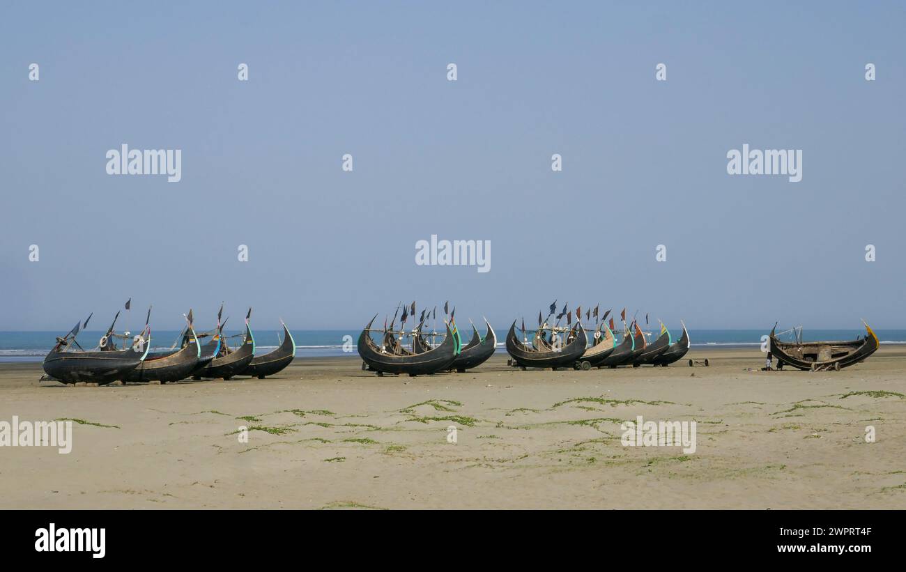 Vue de paysage de bateaux de pêche traditionnels en bois connus sous le nom de bateaux de lune reposant à sec sur la plage d'Inani, Cox's Bazar, Bangladesh Banque D'Images