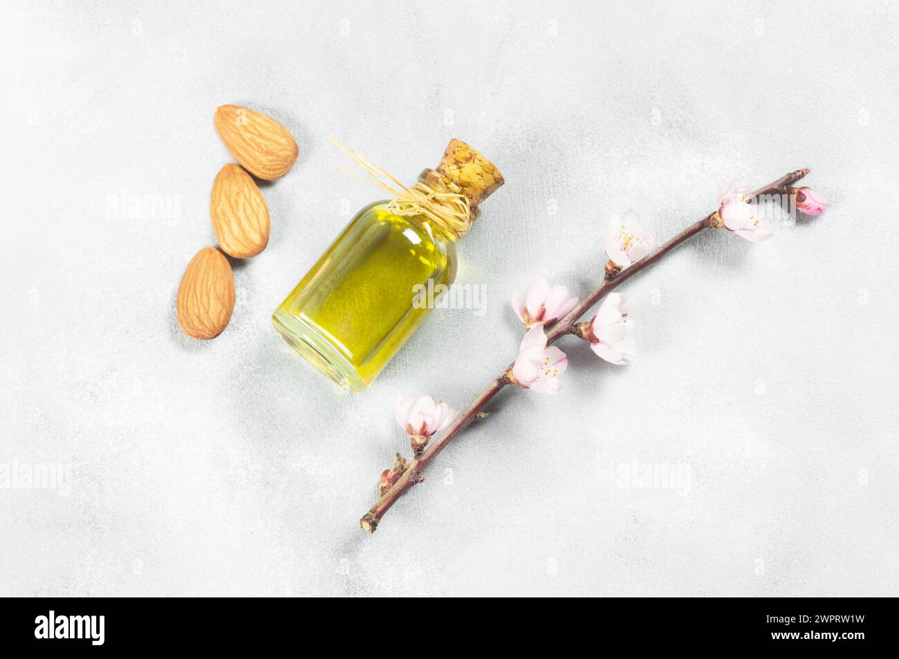 Bouteille en verre d'huile d'amande et noix d'amande , amandes avec fleurs d'amandier sur table. Concept de fond d'amande avec espace de copie Banque D'Images
