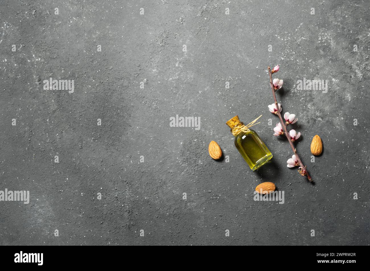 Bouteille en verre d'huile d'amande et noix d'amande , amandes avec fleurs d'amandier sur table. Concept de fond d'amande avec espace de copie Banque D'Images