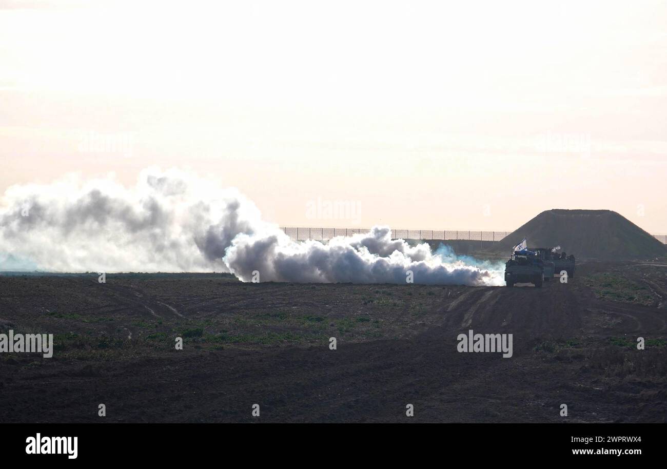 Les véhicules blindés militaires israéliens déploient un écran de fumée à leur retour du centre de Gaza au milieu des combats continus entre Israël et le groupe militant Hamas le 7 mars 2024 à la frontière de Gaza, dans le sud d'Israël. Banque D'Images