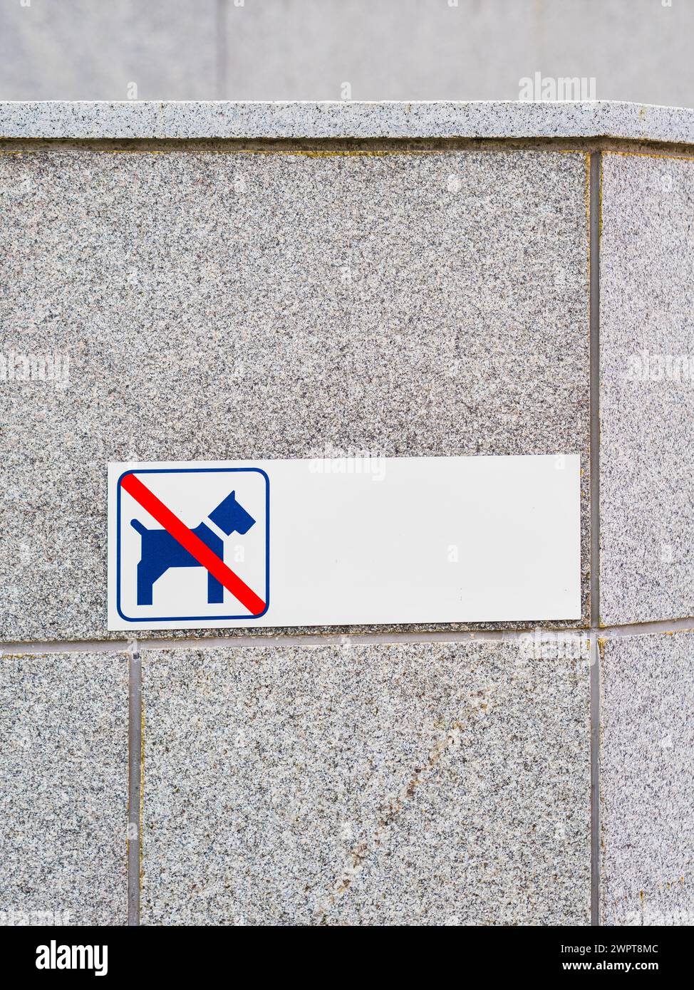 Ce panneau, attaché à un mur de pierre grise en Suède, indique clairement que la zone est interdite à la marche ou au repos des chiens. Le signe bleu et blanc Banque D'Images