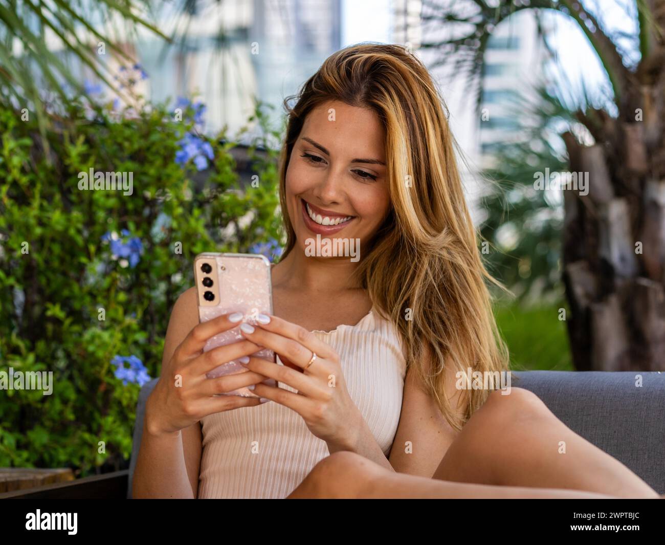 Gros plan d'une belle femme assise sur un canapé tout en écrivant un message sur son smartphone Banque D'Images
