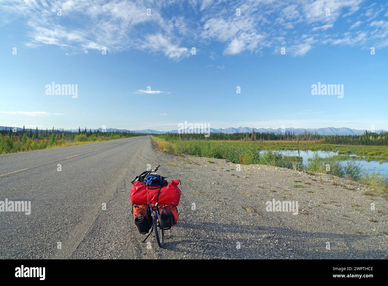 Vélo debout sur une route droite sans fin dans la nature sauvage, tour de vélo, voyage d'aventure, fin d'été, Alaska Highway, Yukon TerritoryCanada Banque D'Images