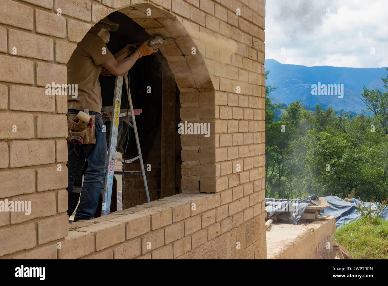 Un menuisier sur un escabeau meulant un cadre en briques adobe pour accueillir une fenêtre, dans un chantier près de la ville coloniale de Villa de Leyva. Banque D'Images