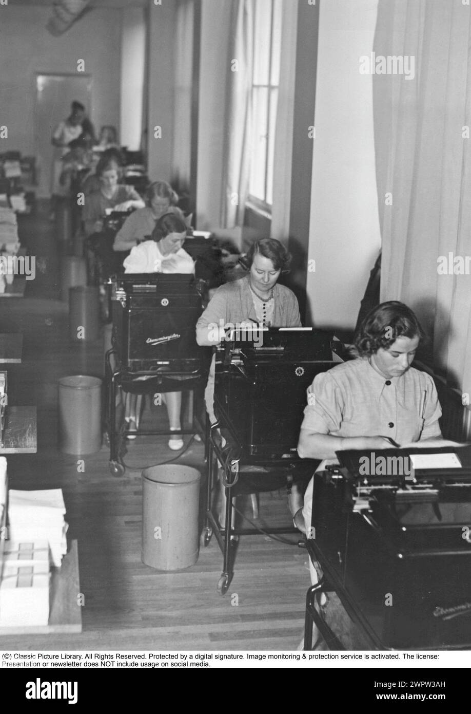 Les filles de bureau dans les années 1940 Femmes à leurs machines à écrire dans une longue rangée le long des fenêtres. 1940 Banque D'Images