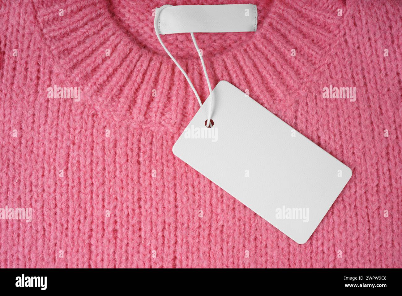 Étiquette de vêtement vierge et étiquette intérieure sur le cou de fond de pull tricoté rose. Maquette, modèle avec carte rectangulaire vide pour le prix ou le texte. Shoppin Banque D'Images
