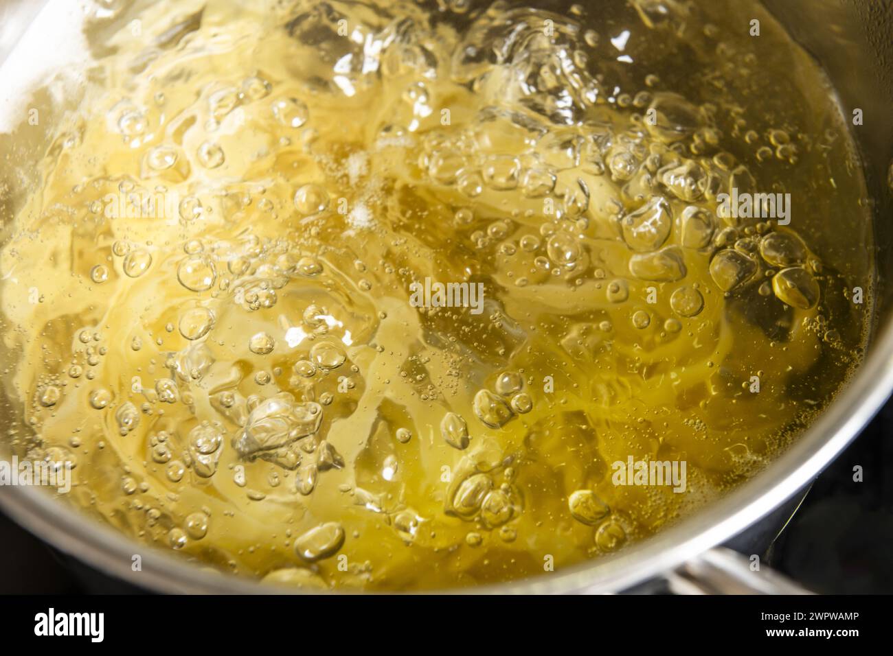 Nouilles cuisant à l'intérieur d'une casserole en acier inoxydable remplie d'eau bouillante bouillante bouillante à 100 degrés Celsius. Banque D'Images