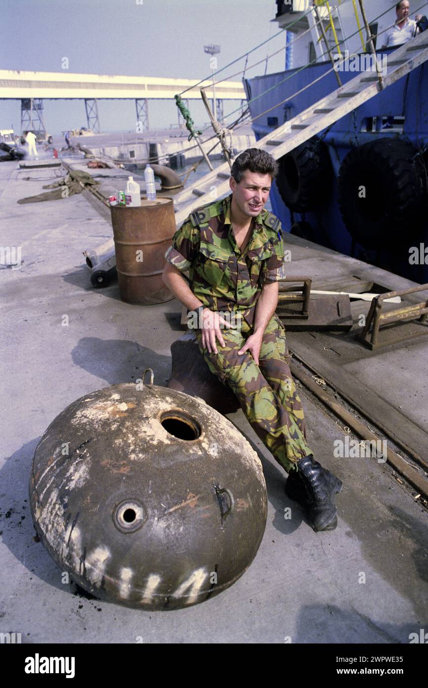 20 mars 1991 sur le quai dans le port d'Shuwaiba, Koweït, un lieutenant de la Marine royale se trouve à côté d'une mine irakiens handicapés. Banque D'Images
