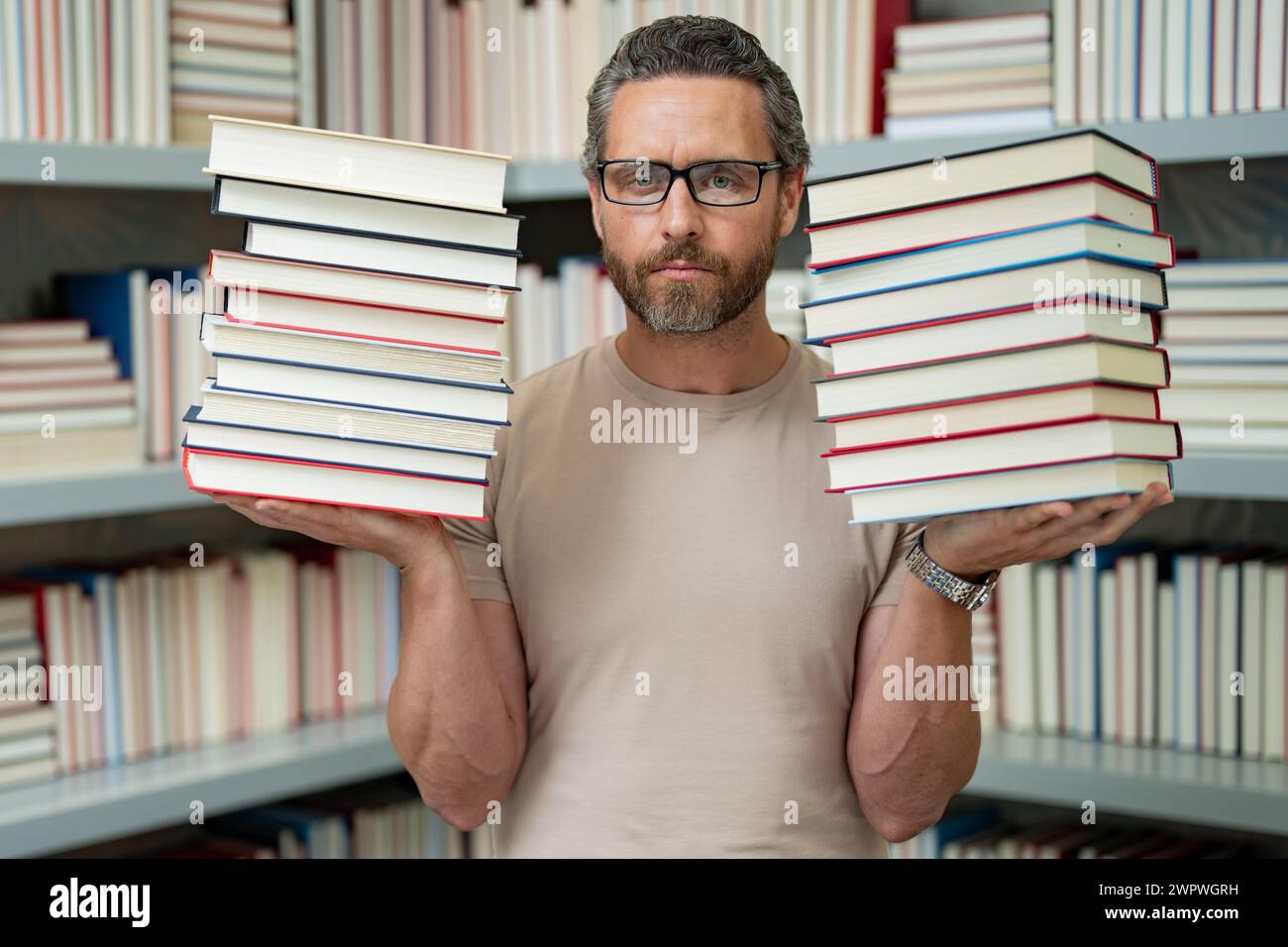 Drôle d'enseignant de tenir beaucoup de livres. Professeur fou avec des livres. Enseignant enthousiaste dans la bibliothèque de livres de l'école. Examen universitaire. Étudier enseigner à l'université. Éducateur Banque D'Images