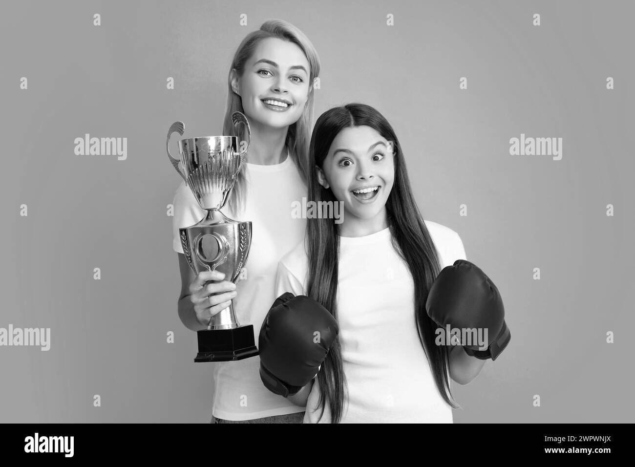 Maman et fille de l'adolescence en gants de boxe tenant le prix gagnant, montrant le trophée sur fond bleu. Parent soutien fille enfant, célébrant la victoire Banque D'Images