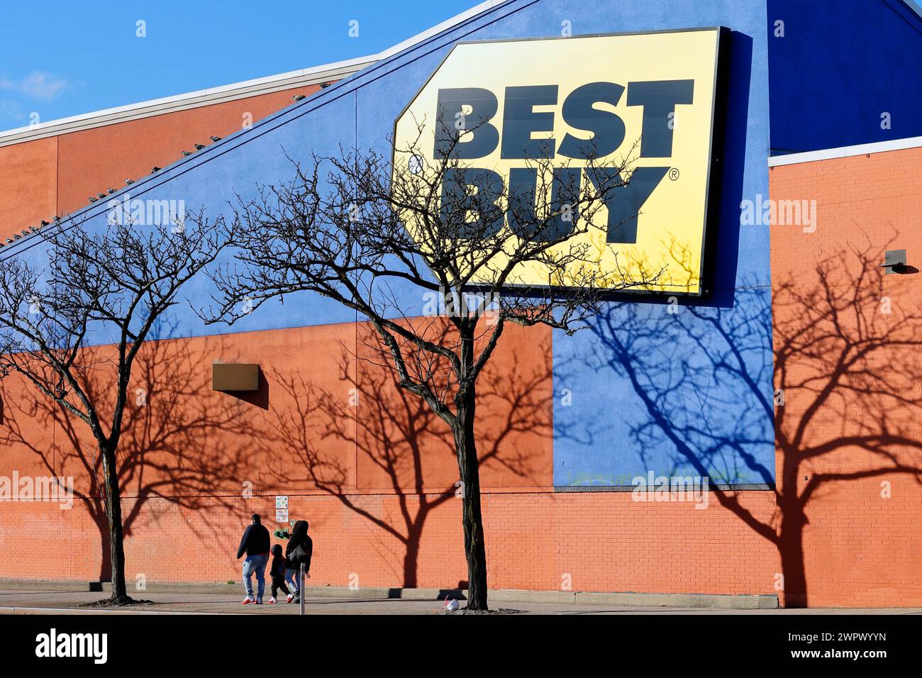 Les gens marchent devant un gigantesque panneau Best Buy sur le côté d'un bâtiment dans le comté de Queens, New York. BEST Buy est un détaillant d'électronique grand public. Banque D'Images