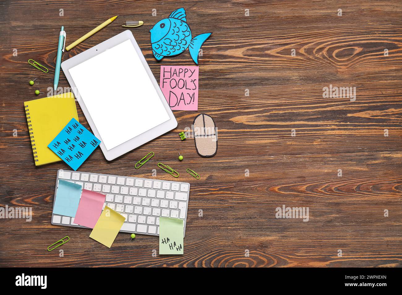Tablette, clavier d'ordinateur, souris de carton et notes adhésives. Farce du jour des fous d'avril Banque D'Images