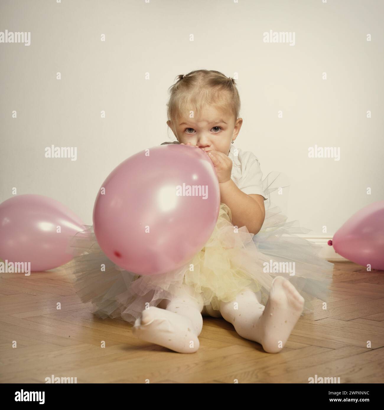 Jolie petite fille de deux ans posant sur plancher de bois pour le portrait Banque D'Images