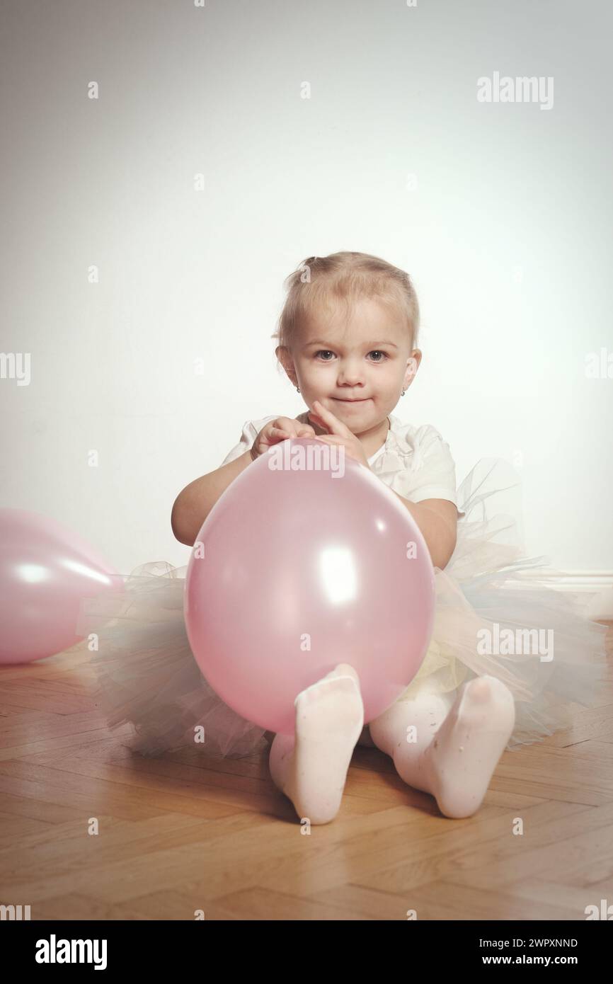 Jolie petite fille de deux ans posant sur plancher de bois pour le portrait Banque D'Images