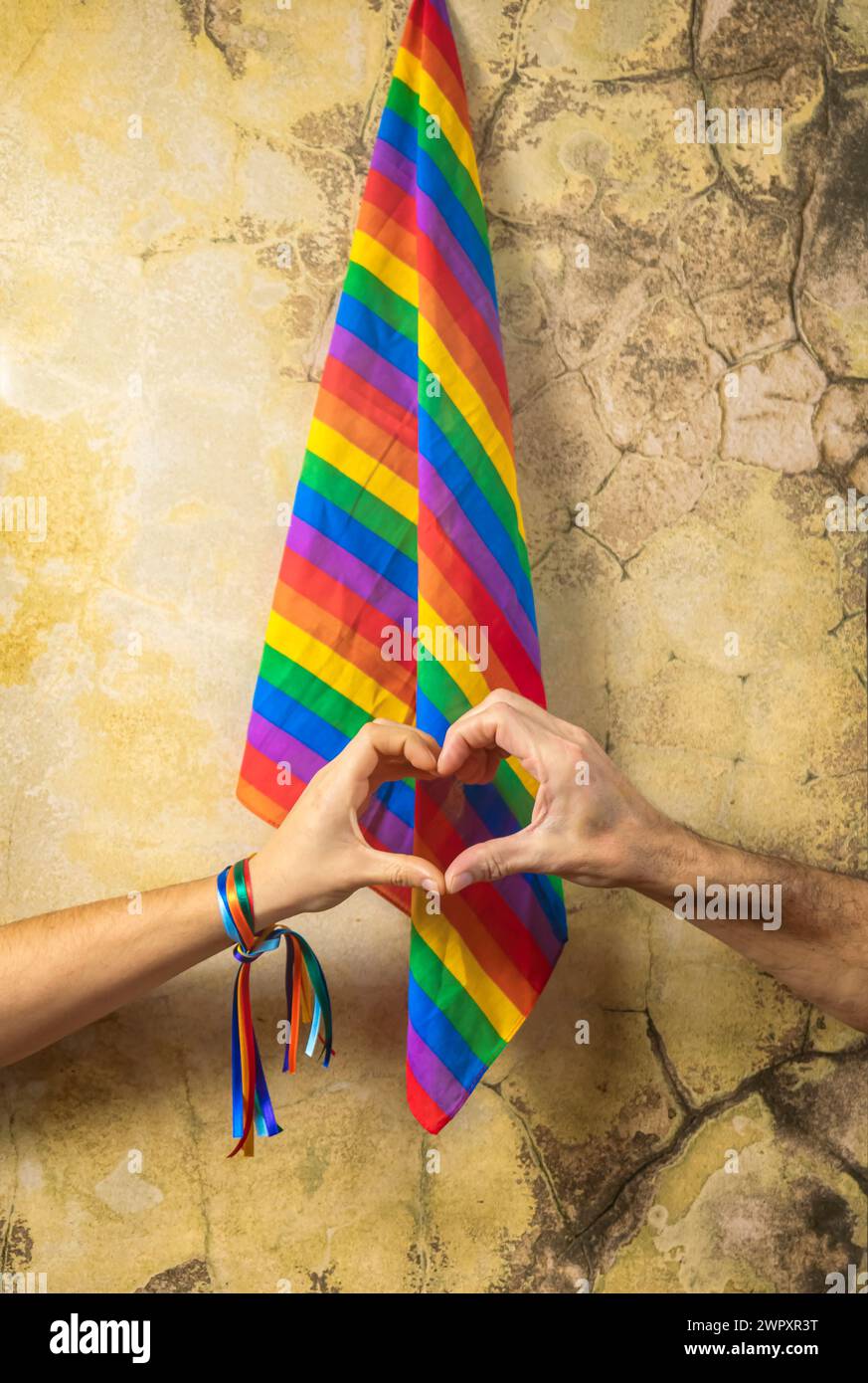 Deux mains se joignent pour former un cœur avec un fond de drapeau LGBT. Concept de fête de la fierté gay et de l'amour entre les différentes races, la paix, les êtres humains contre discr Banque D'Images