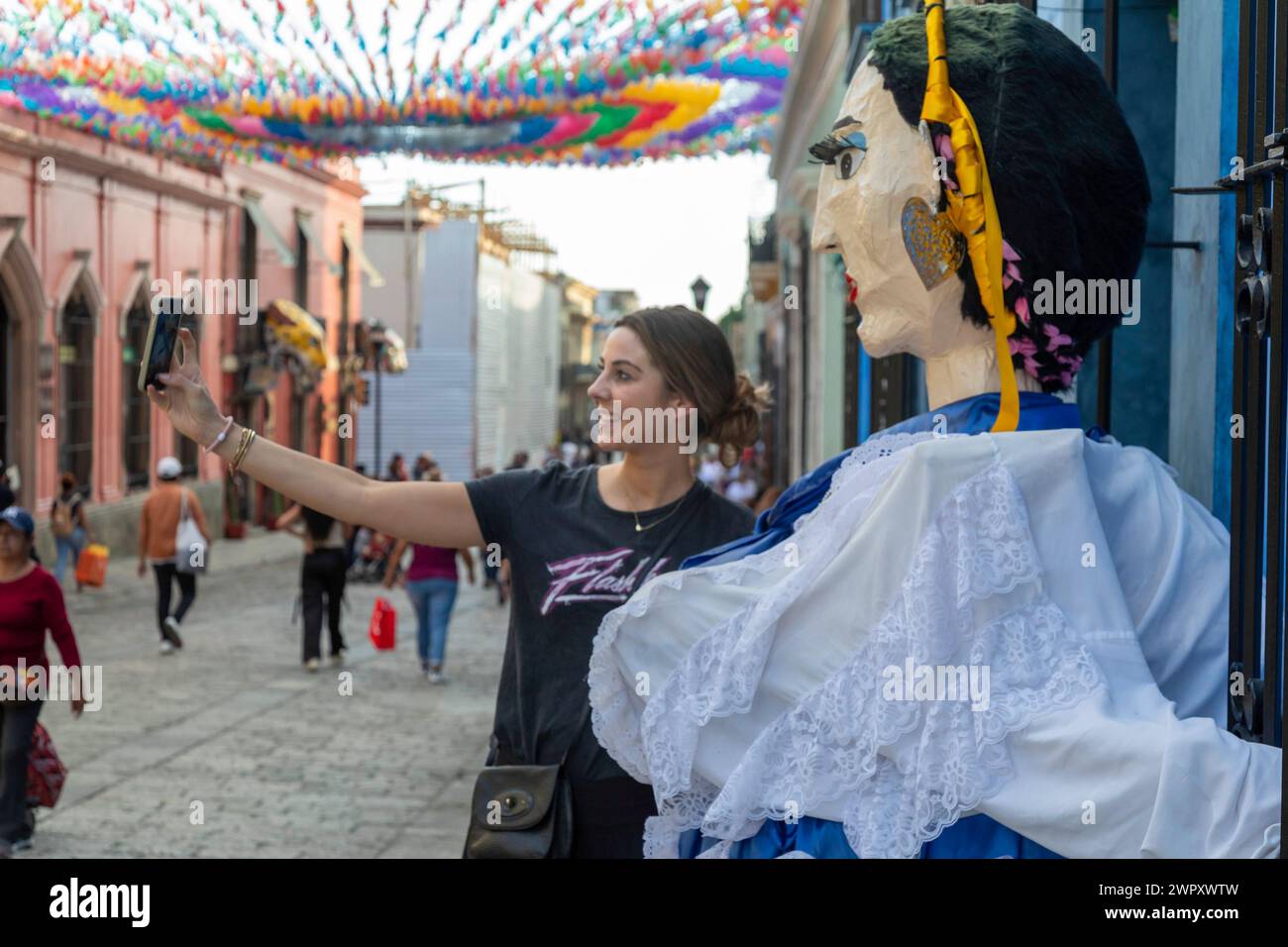 Oaxaca, Mexique - Un touriste prend un selfie avec une marionnette géante en papier mâché sur l'Alcala, une rue piétonne. Banque D'Images