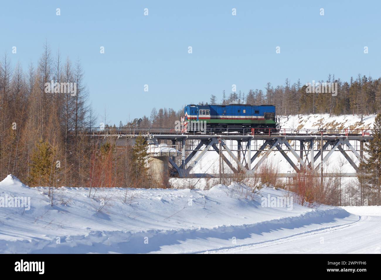 Locomotive diesel sur le pont ferroviaire dans la forêt d'hiver Banque D'Images