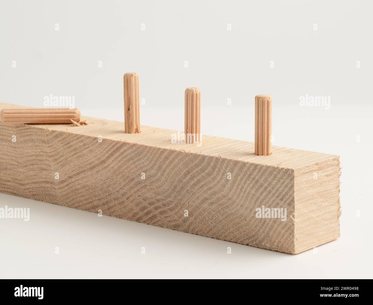 Chevilles cannelées en bois fixées dans une planche de bois isolée sur un fond blanc Banque D'Images