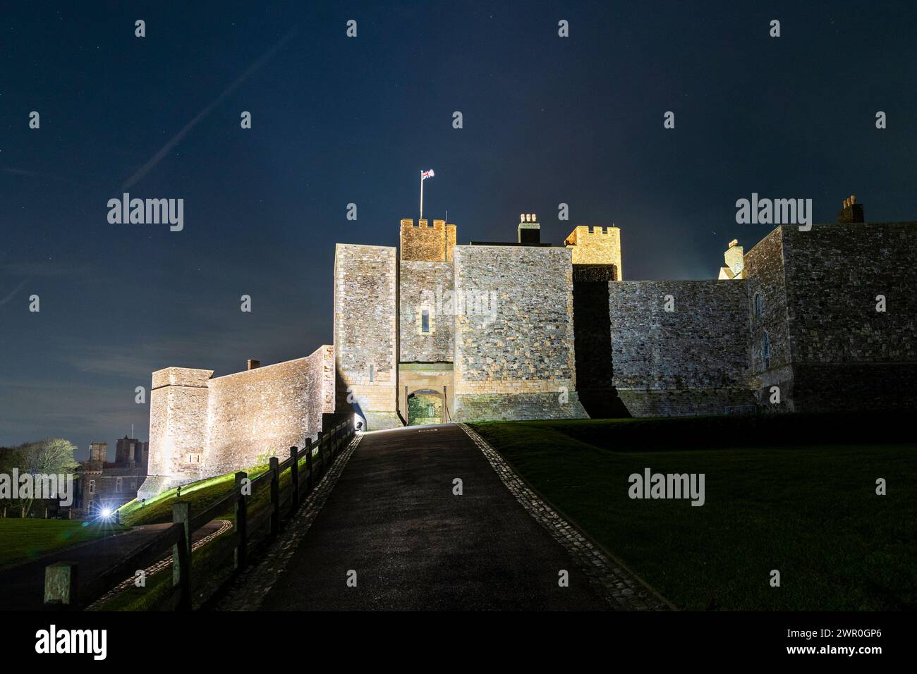 Château de Douvres la nuit, la porte principale dans le mur-rideau entourant le Grand donjon. Murs illuminés, avec le Keep Behind et l'Union Jack flottant Banque D'Images