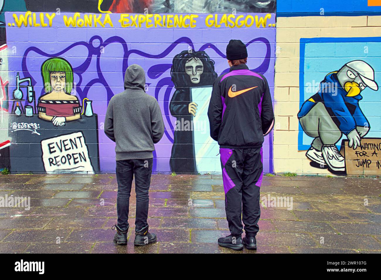 Glasgow, Écosse, Royaume-Uni. 10 mars 2024 : Willy’s Chocolate Experience Fan Kai et son ami sont descendus à l’œuvre d’art sur les rives de la rivière clyde. La fresque murale de la débâcle de Willy Wonka est apparue sur le mur de graffiti côté clyde sur la passerelle clyde. La peinture a été créée par l'artiste Ejek après que l'événement film Experience est devenu l'actualité nationale. L'œuvre représente les actrices qui ont travaillé à l'événement en tant qu'Oompa Loompa et 'The Unknown' du script d'intelligence artificielle. Crédit Gerard Ferry/Alamy Live News Banque D'Images