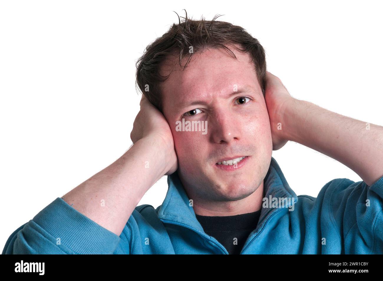 Portrait de tête frontale d'un jeune homme caucasien brune tenant ses mains à ses oreilles avec une expression de colère et regardant la caméra isolée. Banque D'Images
