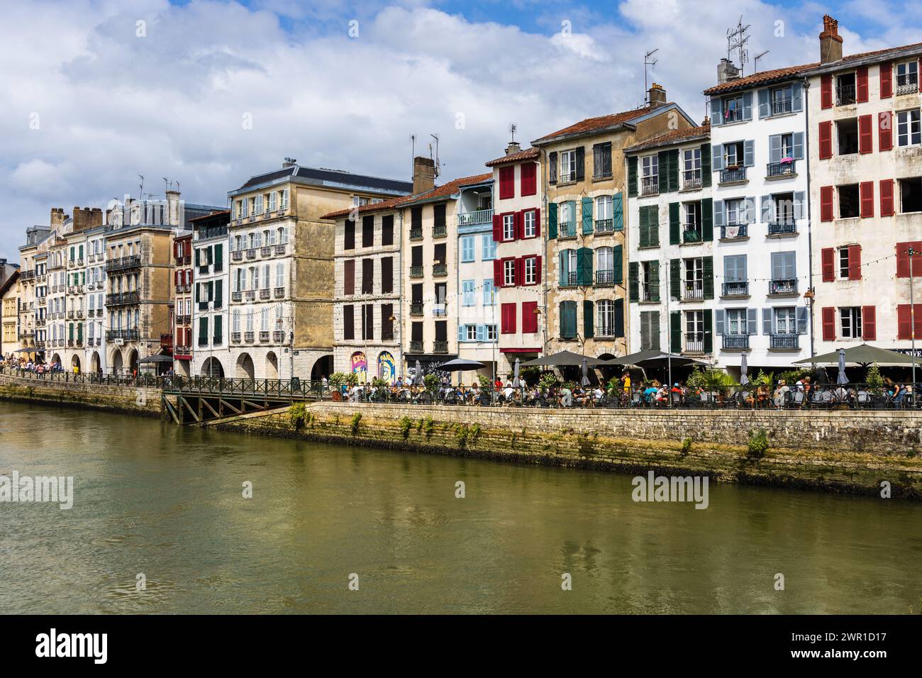 Une vue sur les maisons traditionnelles françaises avec des volets colorés, la rivière Nive, le remblai, et les gens se relaxant dans les cafés de rue. Bayonne, France. Banque D'Images