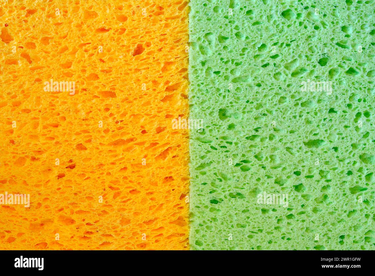 Éponges colorées orange et vertes pour lave-vaisselle avec texture de pores pour des graphiques de fond. Gros plan macro photo de deux tissus éponges domestiques. Banque D'Images