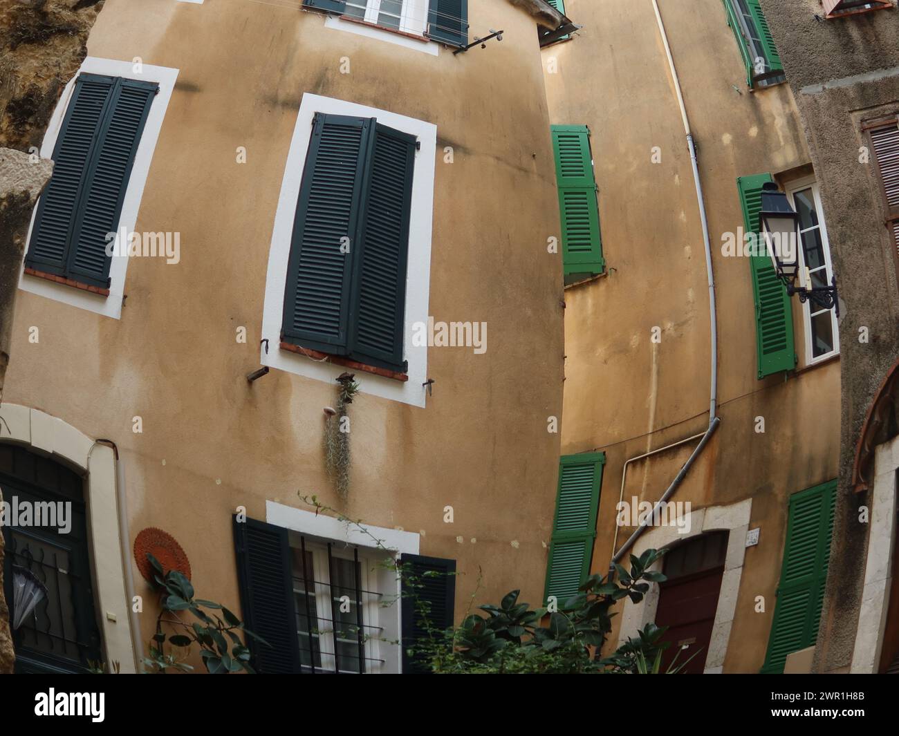Effets photo avec un objectif fisheye : façades courbes de volets sur des bâtiments voisins dans le village médiéval français de Biot. Banque D'Images