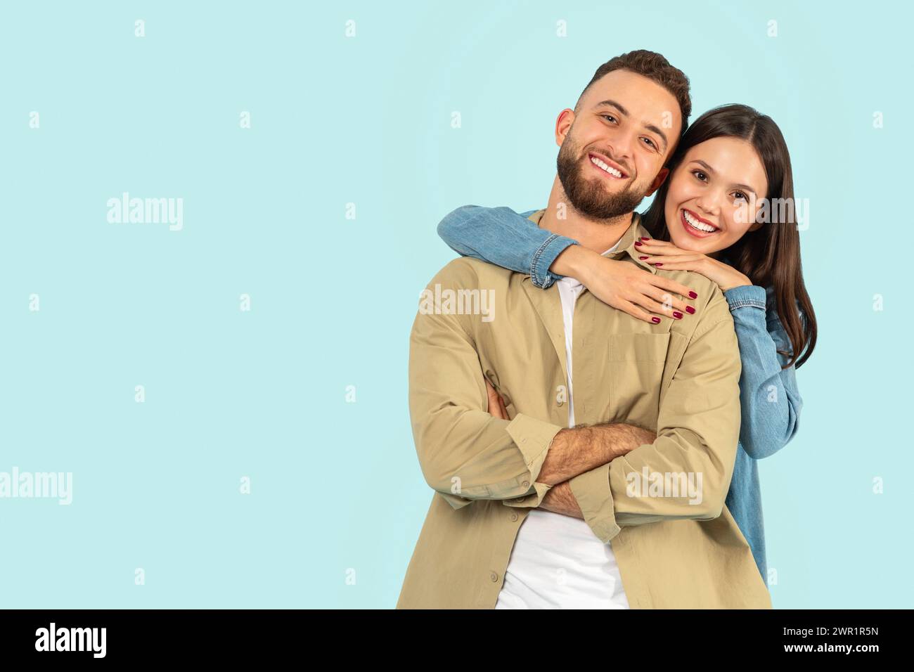 Heureux couple européen jeune serrant tout en posant sur fond bleu Banque D'Images