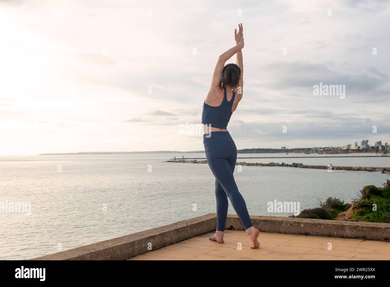 Vue arrière d'une femme qui s'étire et danse au bord de l'océan Banque D'Images