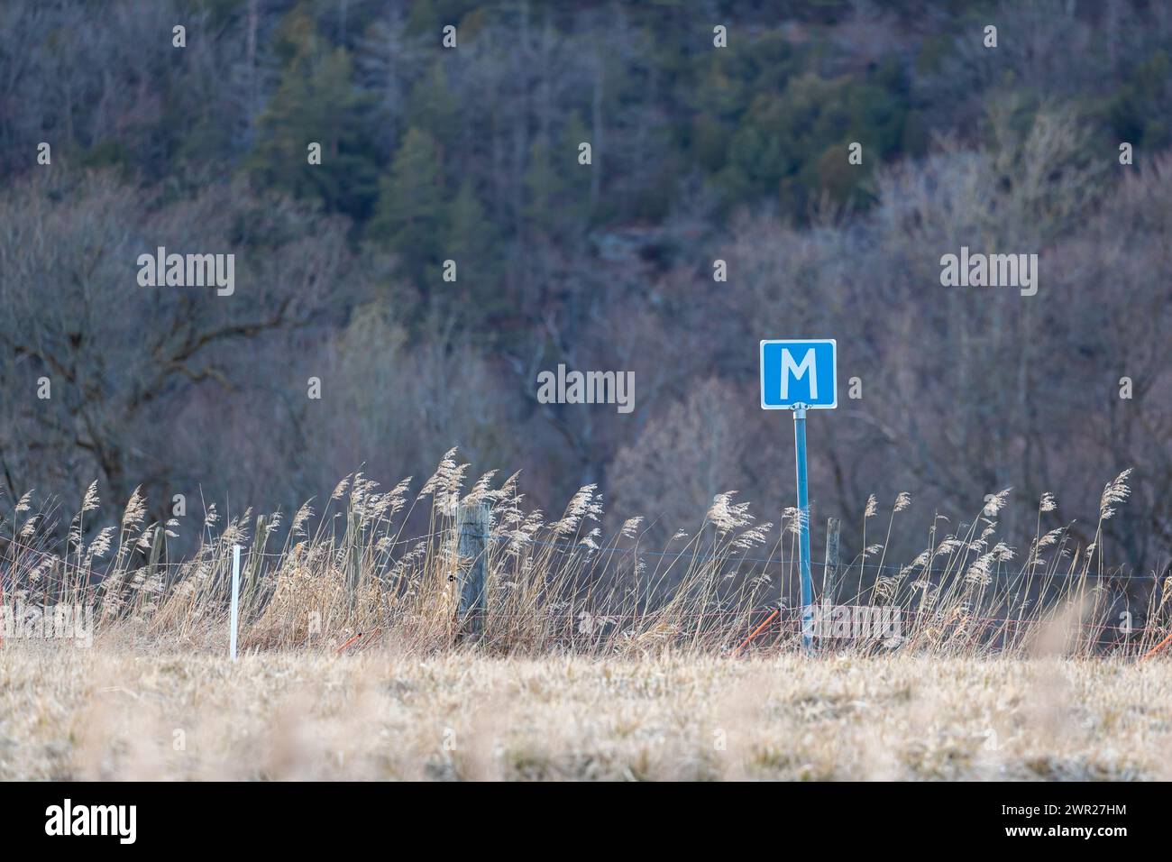 Panneau bleu d'espace de réunion sur un champ de franchissement routier. Herbe sèche et clôture de campagne. Aucune personne visible Banque D'Images